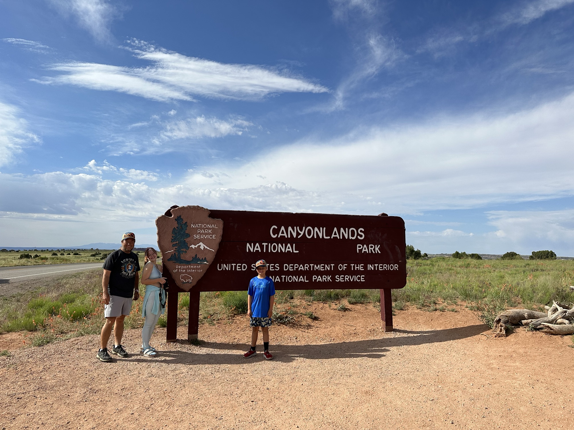 Family standing in front of the Canyonlands National Park Entrance Sign
