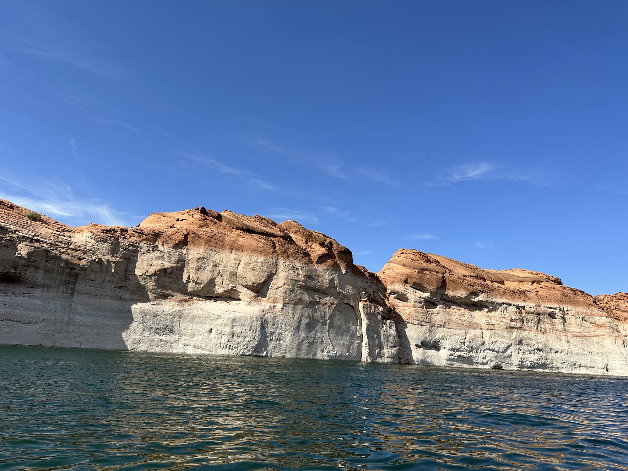 Sandstone cliffs loom along the side of the blue waters of Lake Powell